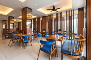 a restaurant with wooden tables and blue chairs at Boss Legian Hotel Powered by Archipelago in Legian