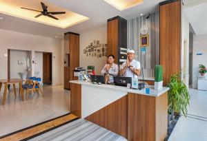 two people standing at a counter in a lobby at Boss Legian Hotel Powered by Archipelago in Legian