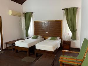 una habitación de hotel con 2 camas y una silla en Hotel Neithal Batticaloa, en Batticaloa