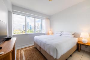 a white bedroom with a large bed and a window at Riverside 2 Bedroom apartment with parking in Brisbane