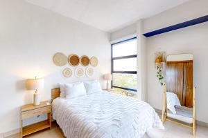 een witte slaapkamer met een bed en een raam bij Vista Bucerias 401 in Bucerías