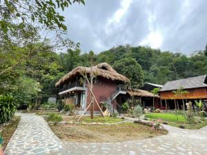 a house with a thatched roof and a pathway at Little Mai Chau Home Stay in Mai Chau