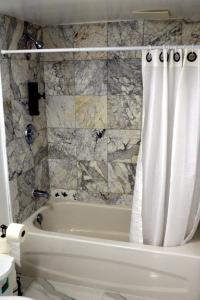 a white bath tub with a shower curtain in a bathroom at DIAMOND PLACE in Brampton