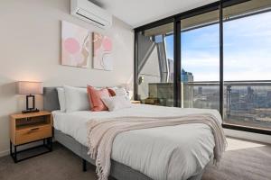 a bedroom with a large bed and large windows at Breathtaking View - 2BR Apt in Melbourne CBD w Gym in Melbourne