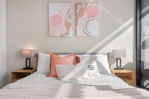 a bedroom with a bed with pink and white pillows at Breathtaking View - 2BR Apt in Melbourne CBD w Gym in Melbourne