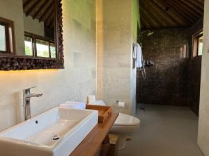 a bathroom with a tub and a toilet and a sink at GRIYA KCB VILLA in Ubud
