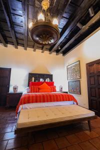 a bedroom with a bed with red pillows and a chandelier at Hotel Casa Bansley in Antigua Guatemala