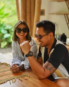 Un uomo e una donna seduti su un tavolo di Sun Sang Eco Retreats a Tabanan