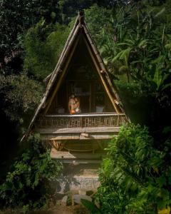 a person sitting on a balcony of a house at Sun Sang Eco Retreats in Tabanan