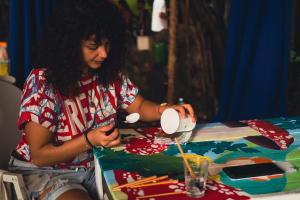a woman sitting at a table cutting paper at Lagarto Na Banana Hostel in Pipa