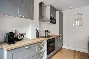 cocina con armarios grises y encimera de madera en Charming flat in Boulogne-Billancourt - Welkeys, en Boulogne-Billancourt
