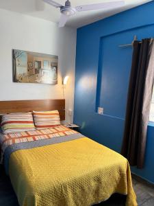 a blue bedroom with a bed with a yellow blanket at Estancia María Bonita Morelia in Morelia