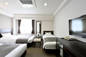 a hotel room with two beds and a flat screen tv at Saijo Urban Hotel in Saijo