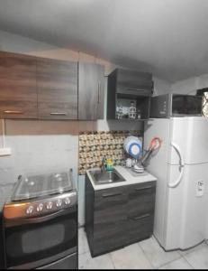 a small kitchen with a stove and a refrigerator at Minimalist House 1br El Bosque in Quito