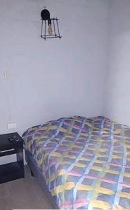Una cama con un edredón colorido en un dormitorio en Minimalist House 1br El Bosque, en Quito