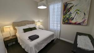 a bedroom with a bed and a painting on the wall at Hatbox House in Perth