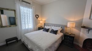 a bedroom with a bed with two pillows and a mirror at Hatbox House in Perth