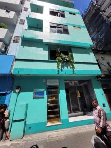 Ontrack Travel Transit Hotel في مدينة ماليه: مبنى ازرق فيه ناس تمشي امامه