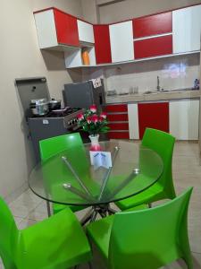 una mesa de cristal con sillas verdes en la cocina en DEPARTAMENTOS SUCRE PCL, en Pucallpa