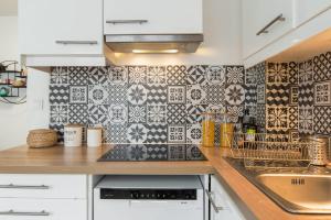 a kitchen with black and white tiles on the wall at Beautiful and bright T2 in Villeurbanne near Lyon - Welkeys in Villeurbanne