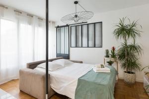 a bedroom with a bed and two potted plants at Beautiful and bright T2 in Villeurbanne near Lyon - Welkeys in Villeurbanne