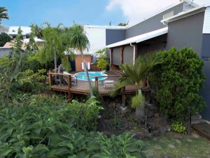 a house with a wooden deck with a table at La Buddha Case in Étang-Salé