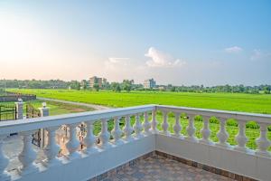 - un balcon blanc avec vue sur un champ verdoyant dans l'établissement Lumbini Five Elements Hotel, à Rummindei