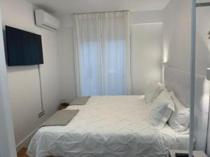 een slaapkamer met een wit bed en een televisie bij Precioso, barrio Magdalena in Ferrol