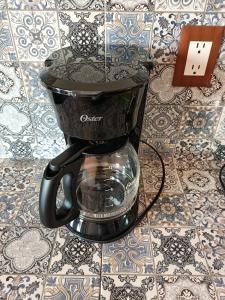 a black coffee maker sitting on a tile floor at Alojamiento HM in Cholula