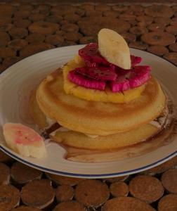 a stack of pancakes with sliced fruit on a plate at JEJU Cottages in Kuta Lombok