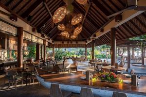 un ristorante con tavoli e sedie e una barca sul pavimento di Bali Emerald Apartments a Sanur