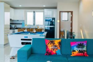 a blue couch with tropical pillows in a living room at Ocean Pool Villa Pattaya in Bang Sare