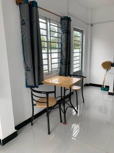 a dining room with a wooden table and chairs at Home Daun Kam in Kampot