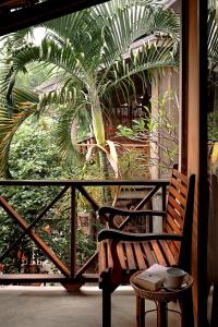 a wooden bench sitting on a balcony with a palm tree at My Dream Boutique Resort in Luang Prabang