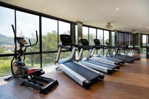 - une rangée d'appareils de cardio-training dans une salle de sport dotée de fenêtres dans l'établissement Citygate Condo P609, Kamala Hill View, near Kamala Beach and Fantasea, à Kamala Beach