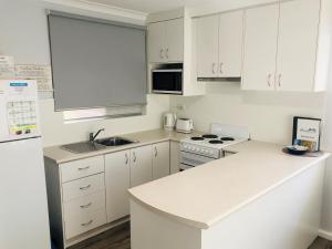 uma cozinha com armários brancos e um balcão branco em API Middleton Beach Front Apartments Albany em Albany