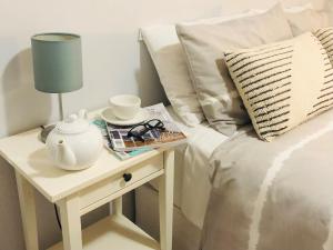 a bed with a table with a lamp and a tea pot on it at API Middleton Beach Front Apartments Albany in Albany
