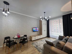 ein Wohnzimmer mit Sofa und Tisch in der Unterkunft Уютные апартаменты в элитном комплексе in Almaty