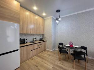 eine Küche mit einem Tisch und einem weißen Kühlschrank in der Unterkunft Уютные апартаменты в элитном комплексе in Almaty
