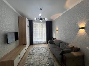 ein Wohnzimmer mit Sofa und Fernseher in der Unterkunft Уютные апартаменты в элитном комплексе in Almaty + 2 Fotos