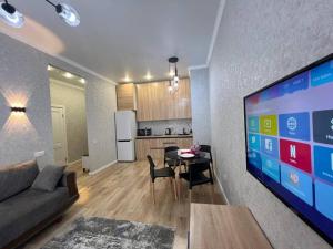 ein Wohnzimmer mit Couch und Tisch und eine Küche in der Unterkunft Уютные апартаменты в элитном комплексе in Almaty