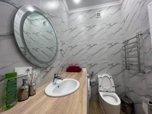 ein Badezimmer mit Waschbecken, Toilette und Spiegel in der Unterkunft Уютные апартаменты в элитном комплексе in Almaty