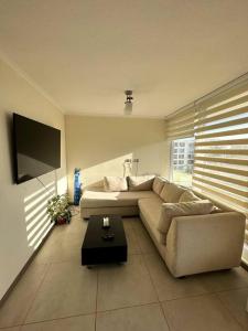 een woonkamer met een bank en een flatscreen-tv bij Duplex 2D 2B con vista al mar in La Serena