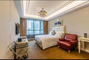 ein Hotelzimmer mit einem Bett und einem Stuhl in der Unterkunft Wealthy All Suite Hotel Suzhou in Suzhou