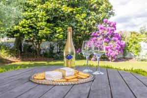 a table with a plate of cheese and wine glasses at 2 Bedroom Home away from Home near CBD & private parking in Hamilton