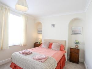 a bedroom with a bed with pink sheets and a window at Bro Dawel in Beaumaris