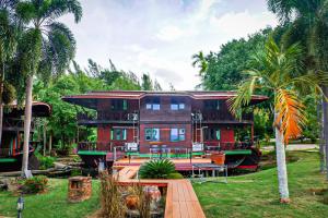 ein Haus auf einem Boot in einem Garten mit Palmen in der Unterkunft Kaengkrachan Boathouse Paradise Resort in Kaeng Kachan