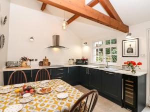 a kitchen with black cabinets and a table with food on it at Croft Cottage in Long Marton