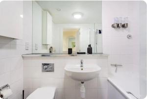 La salle de bains blanche est pourvue d'un lavabo et d'une baignoire. dans l'établissement Luxury Central London Apartment, à Londres