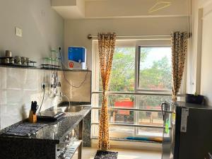 una cocina con encimera y una ventana con cortinas en Compact yet beautiful 1bhk 201, en Bangalore